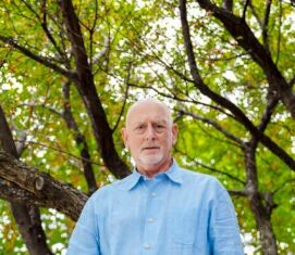 Despite medical advances, life expectancy gains are slowing A man in a blue collared shirt stands outside in front of a tree.