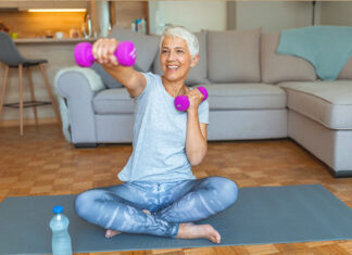 Mini Medical School 2025 program starts soon Woman sits with crossed leg on the floor on a yoga mat holding weights with one arm extended out