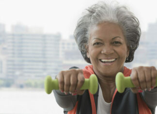 Exercise supports healthy aging — and more older adults need to get moving, report says black older woman holding two dumbbells, exercising