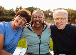 New toolkit helps rural communities plan for aging together Three older adults sitting on grass next to each other smiling at camera