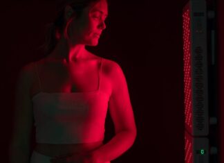 Bountiful Benefits of Red Light Therapy: Anti-Aging, Heart Health, Sleep and More Woman Standing Near Red Light Therapy Panel