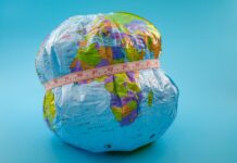 Thirty years of data reveal changing heart health trends in obesity globe with measuring tape wrapped around it. Isolated on blue background.