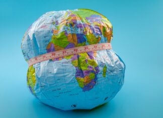 Thirty years of data reveal changing heart health trends in obesity globe with measuring tape wrapped around it. Isolated on blue background.