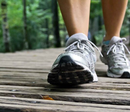 experts say hitting a certain “golden step” count each day could slow how fast your brain ages An older adult taking a healthy daily walk in a park, representing exercise benefits for cognitive health.